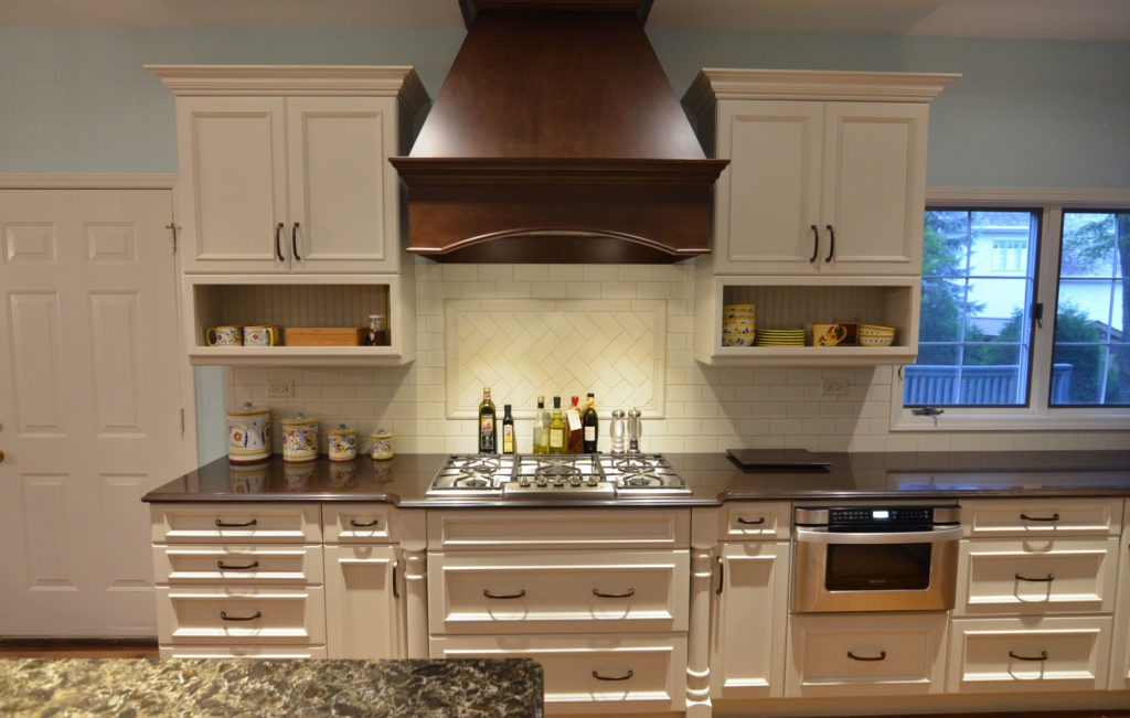 Updated kitchen with white cabinets, dark stone countertops, white tile backsplash.