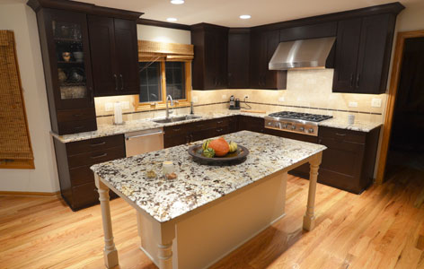 Kitchen with large stone island & countertops deep brown cabinets stainless steel appliances
