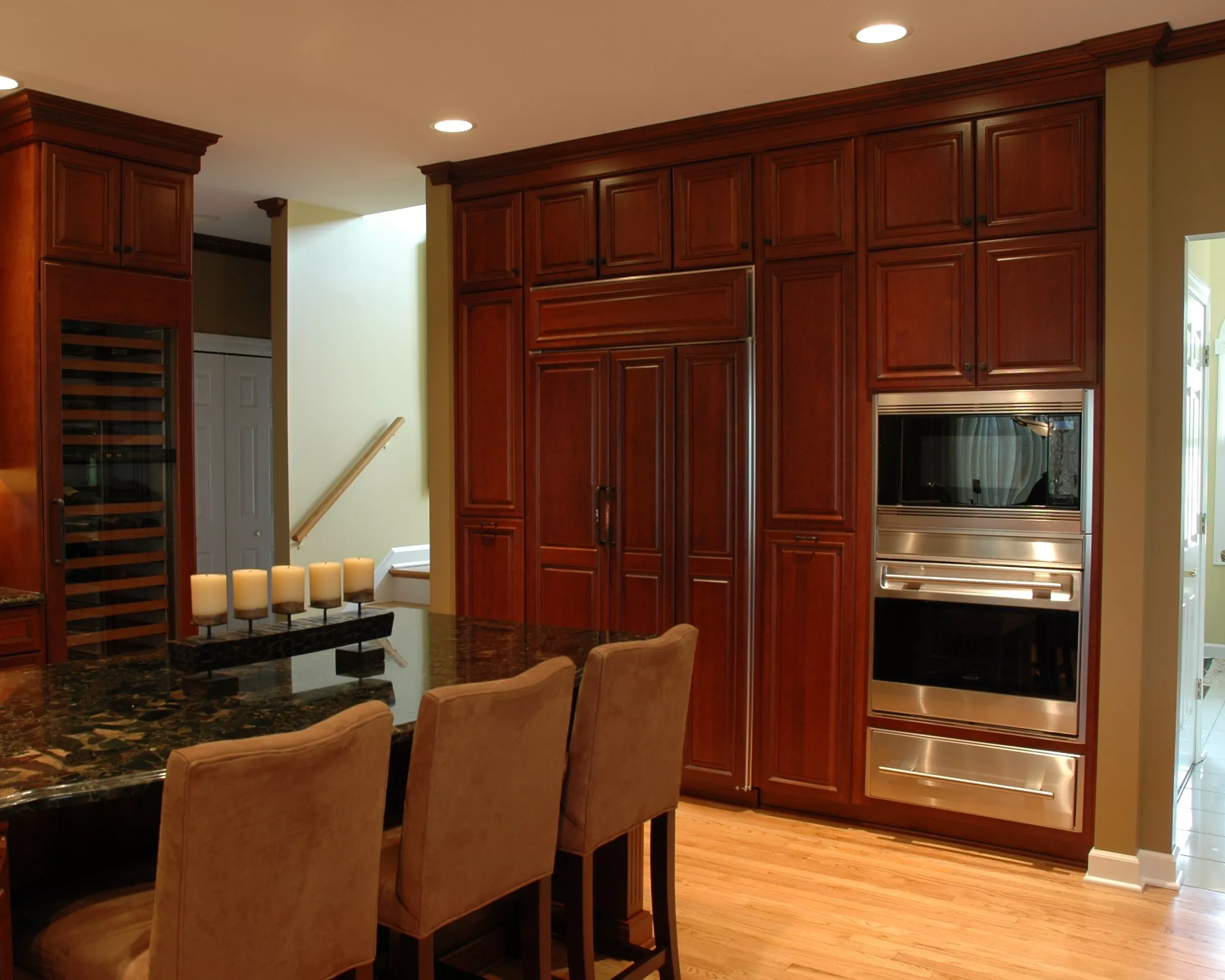Kitchen with multifunctional ovens, a wine reserve and red wood cabinets