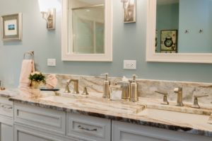 Remodeled bathroom with white traditional style cabinets and light granite countertop with two sinks. Brushed nickel faucets, light blue wall.