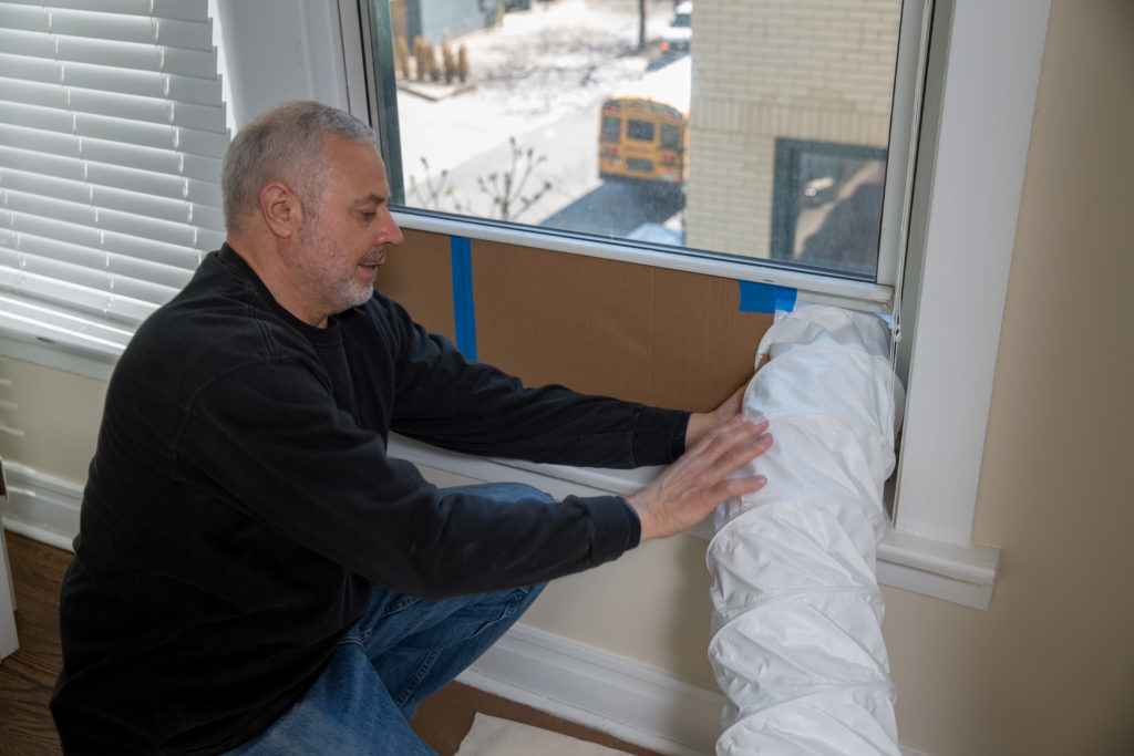 the kitchen master contractor holding vent in window to clean renovation air