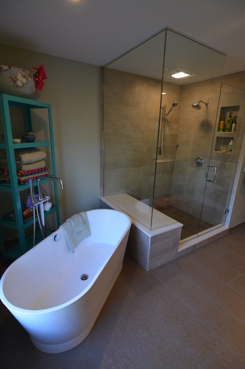 bathroom remodel glass shower freestanding garden tub grey tile flooring blue shelving unit