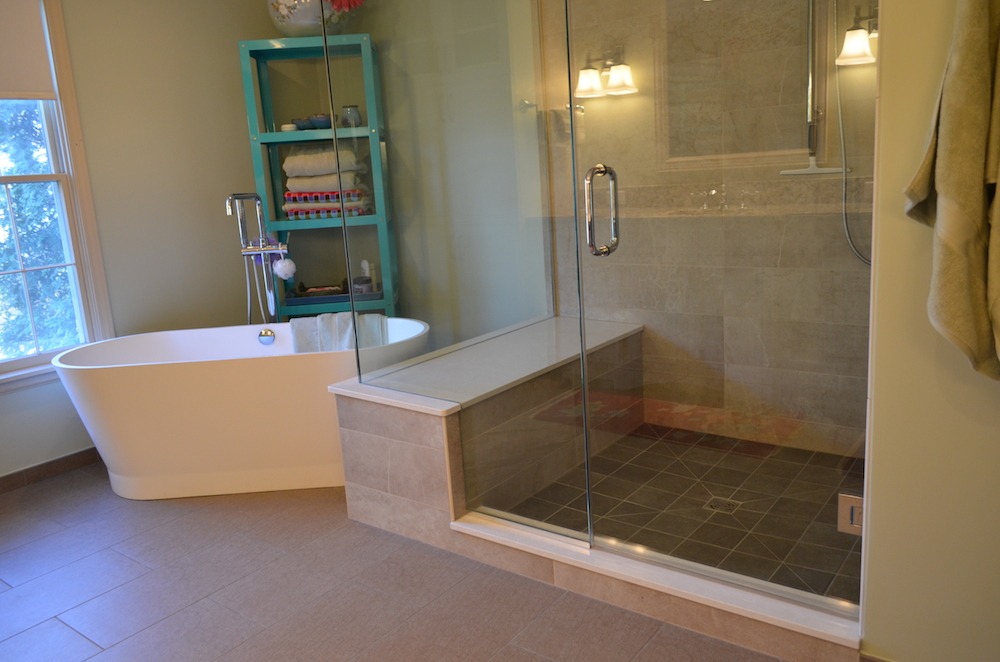 bathroom renovation glass shower freestanding garden tub grey tile flooring blue shelving unit