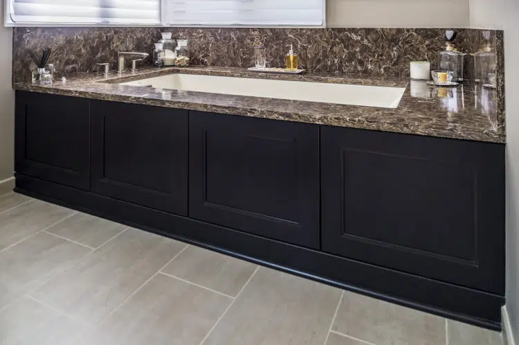 Built-in bathtub with stone counter around it in master bathroom