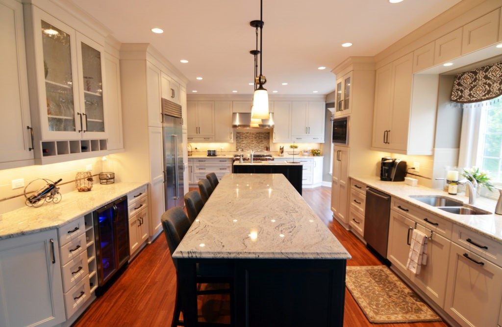 galley kitchen renovation marble island white cabinetry hardwood flooring recess lighting