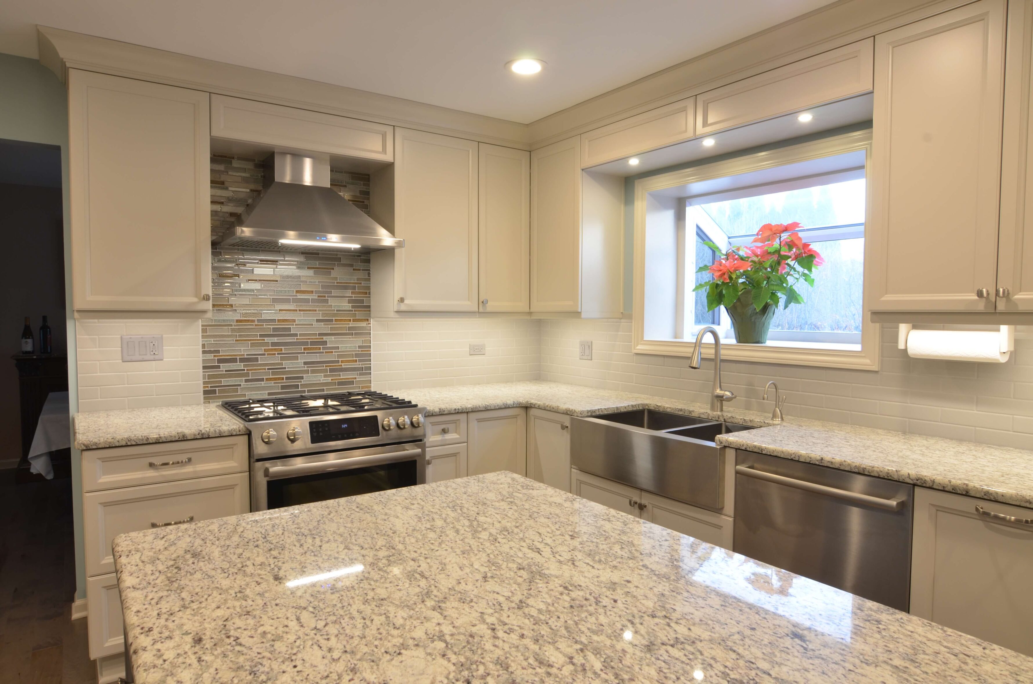 corner view of bright kitchen renovation flower in window sill quartz countertop white cabinetry