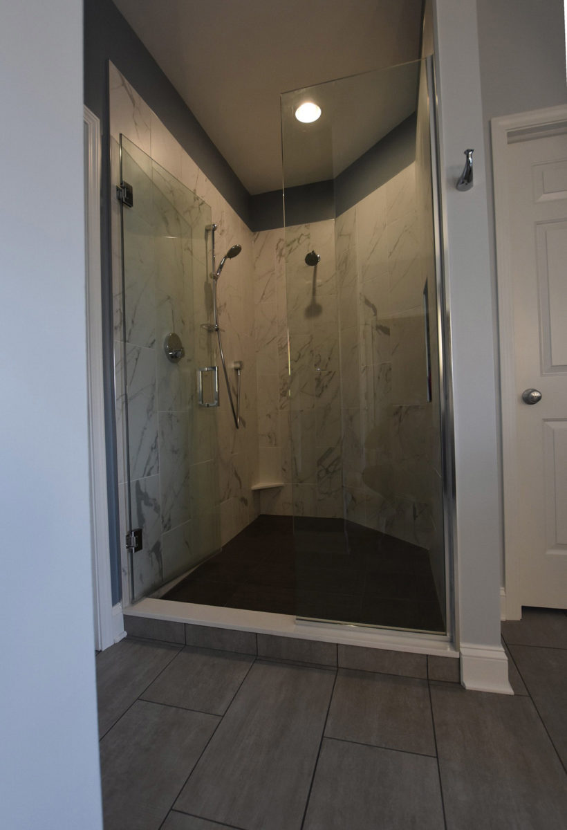 Walled-in shower with glass doors and marble walls
