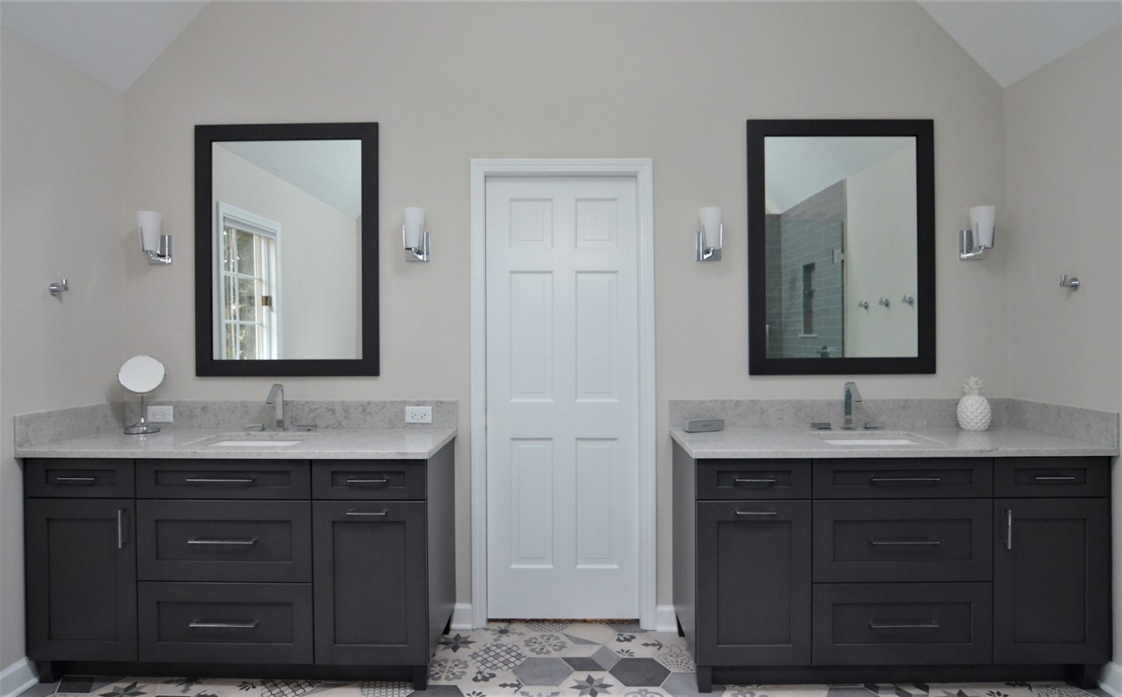 Two separate bathroom sinks and cabinets with a door between them