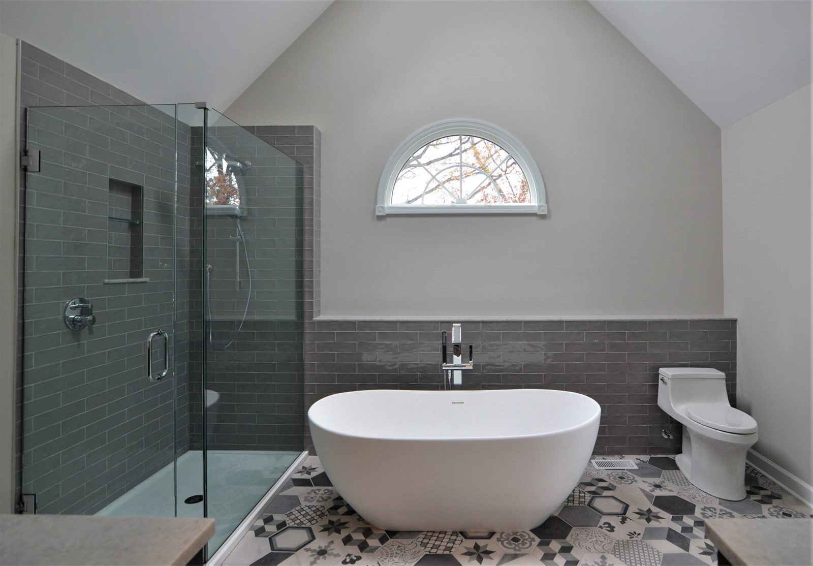 Bathroom with free-standing bathtub, glass corner shower, toilet and window