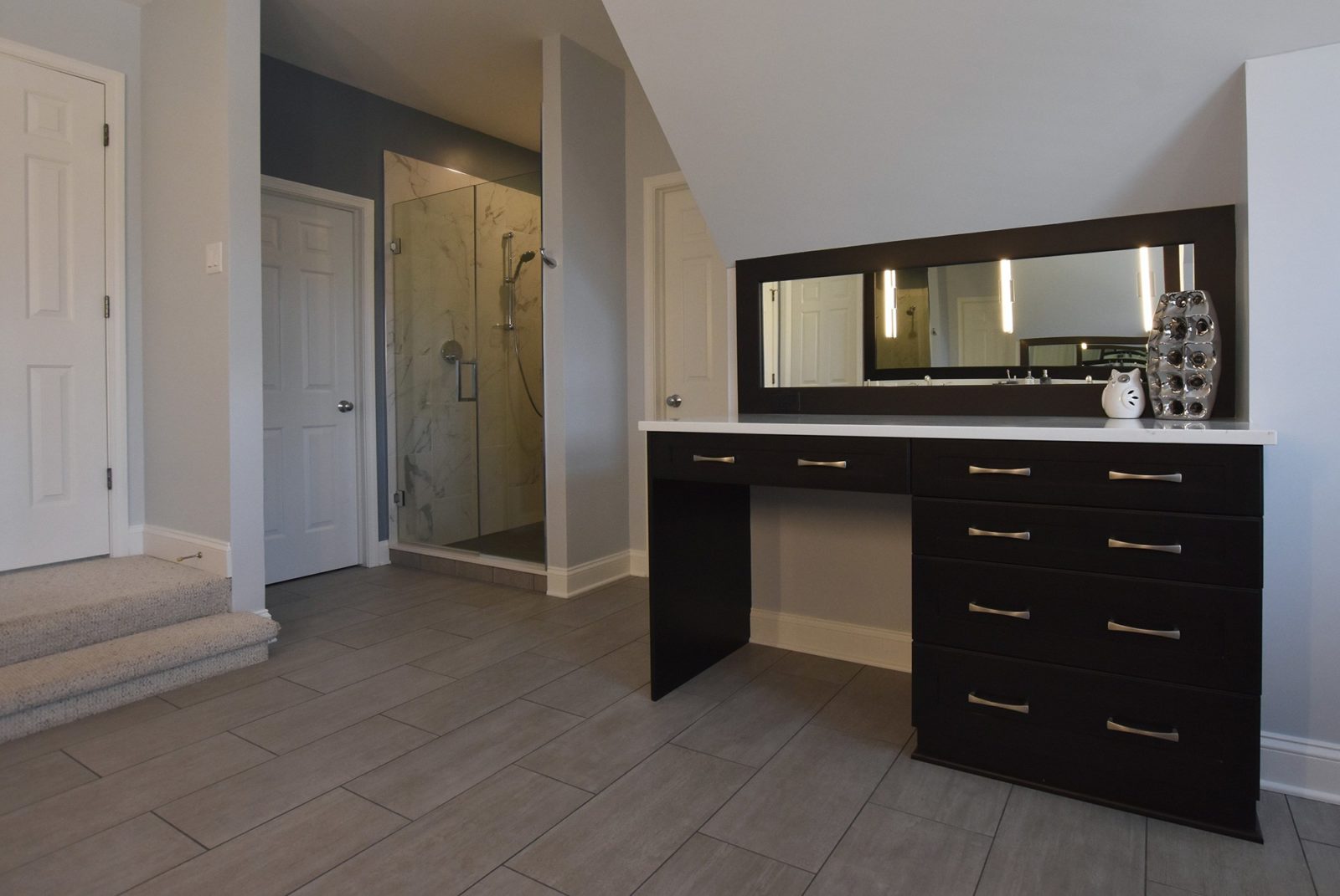 Bathroom with a countertop along one wall and walled-in shower in a corner