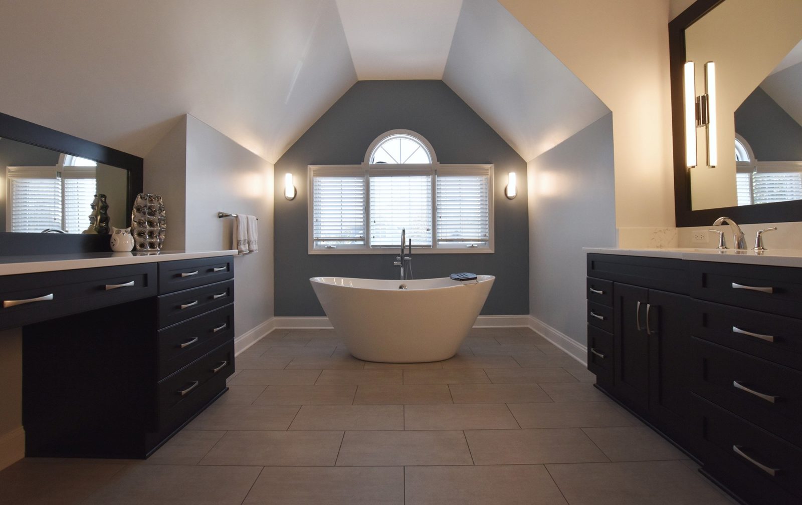 Bathroom with free-standing bathtub in middle, windows, sinks on one side and counter on other side