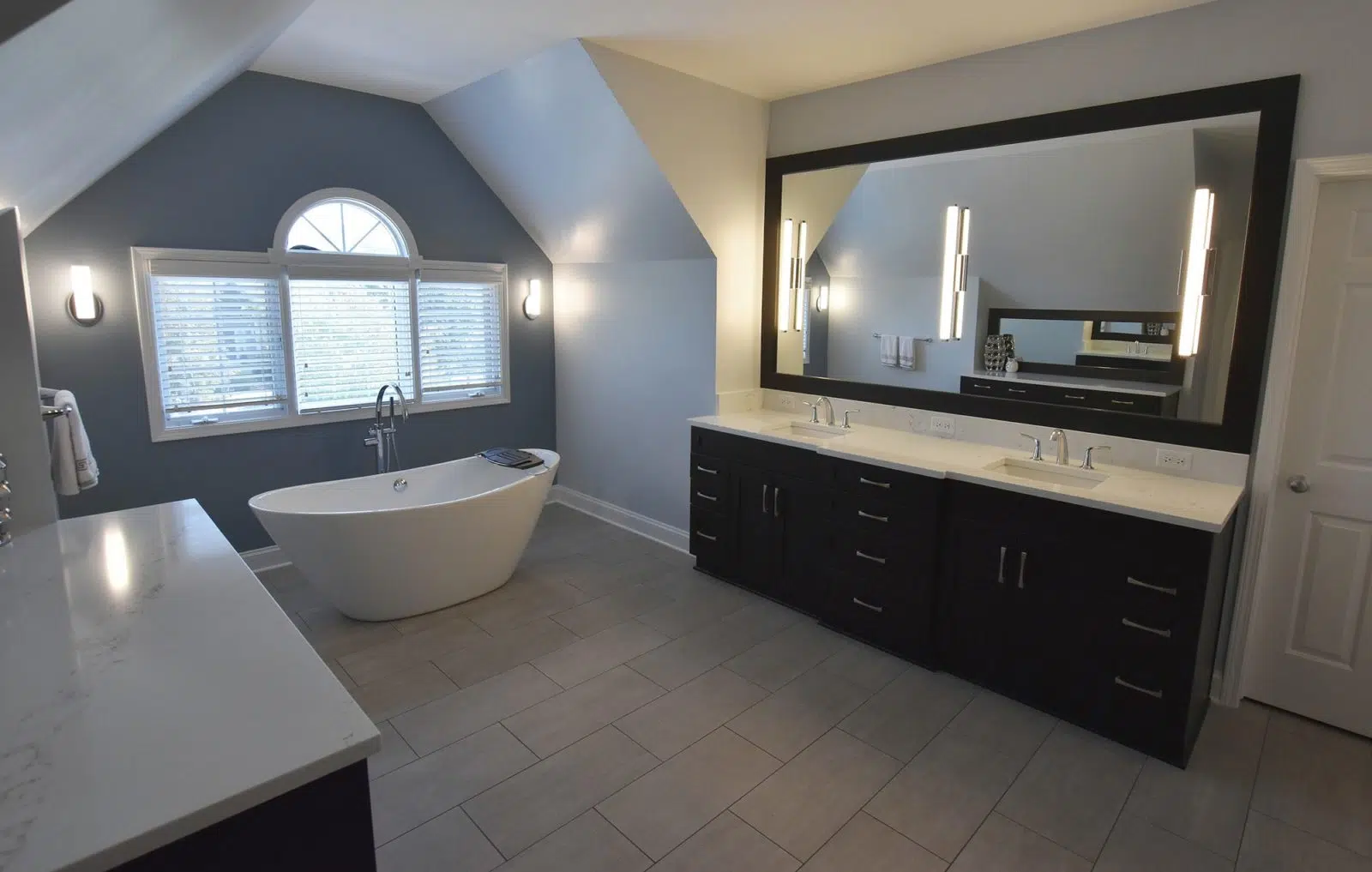 Bathroom with free-standing bathtub in middle, windows, sinks on one side and counter on other side