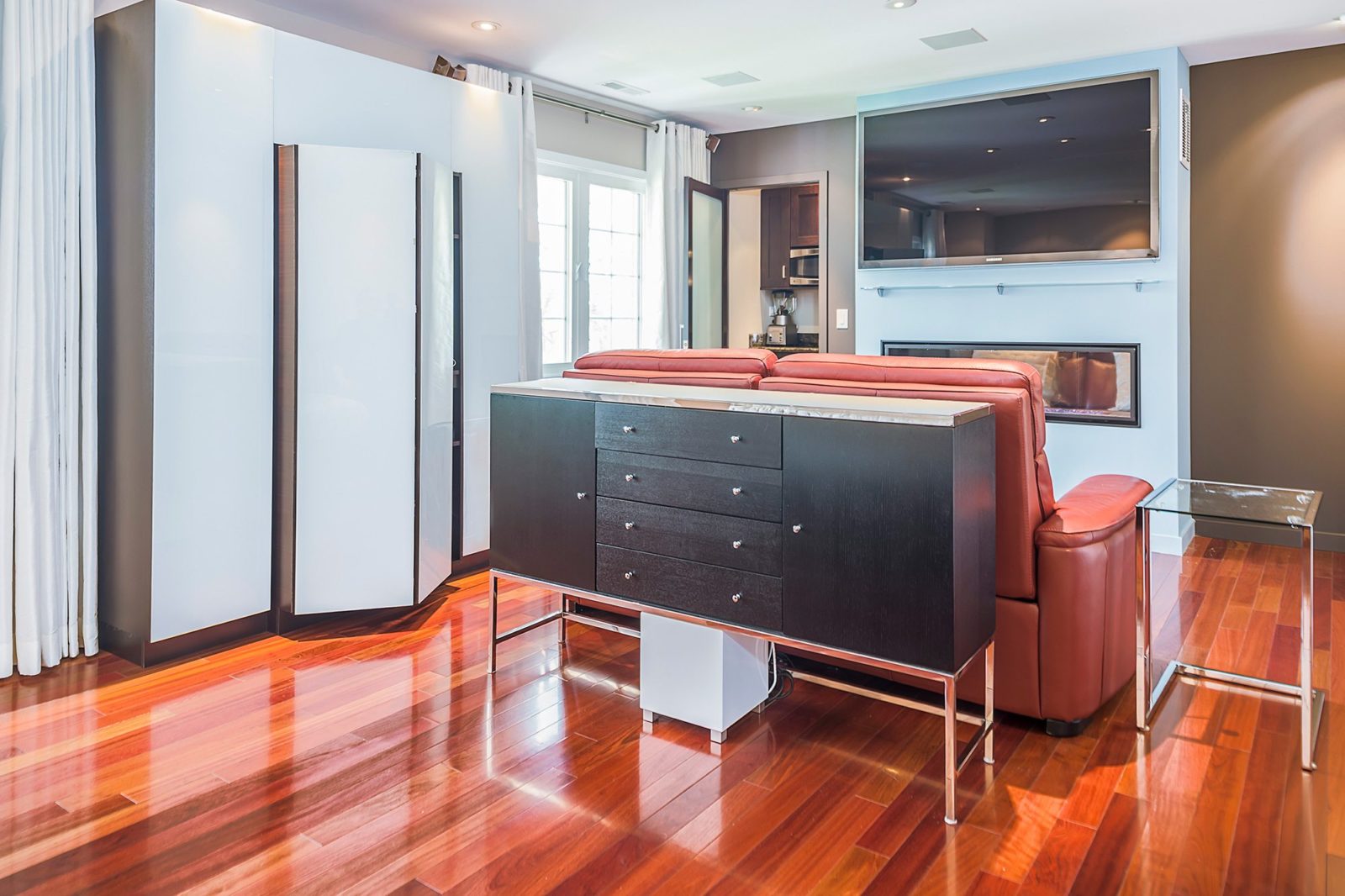 hotel room remodel red couch black storage stand shiny hardwood floors mounted tv hidden storage