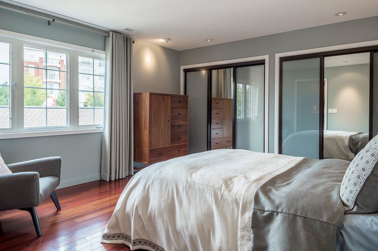bedroom renovation hardwood floors double closets oak dresser grey sitting chair comfortable bed