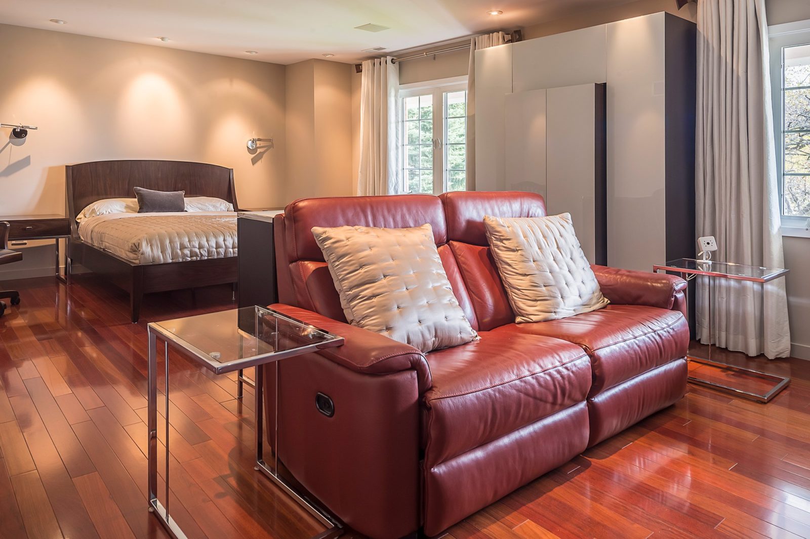 hotel room renovation queen bed red recliner chair between glass side tables bright modern