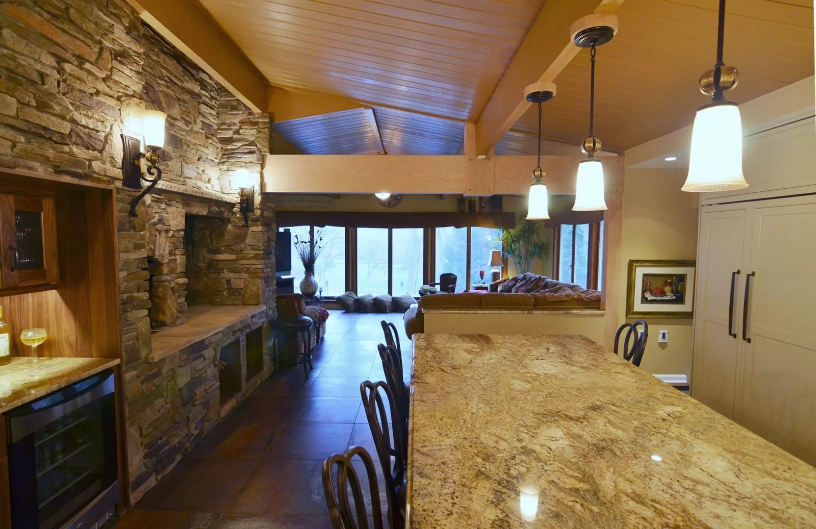 Kitchen with appliances, kitchen table with chairs, stonework wall with stone oven, and living room