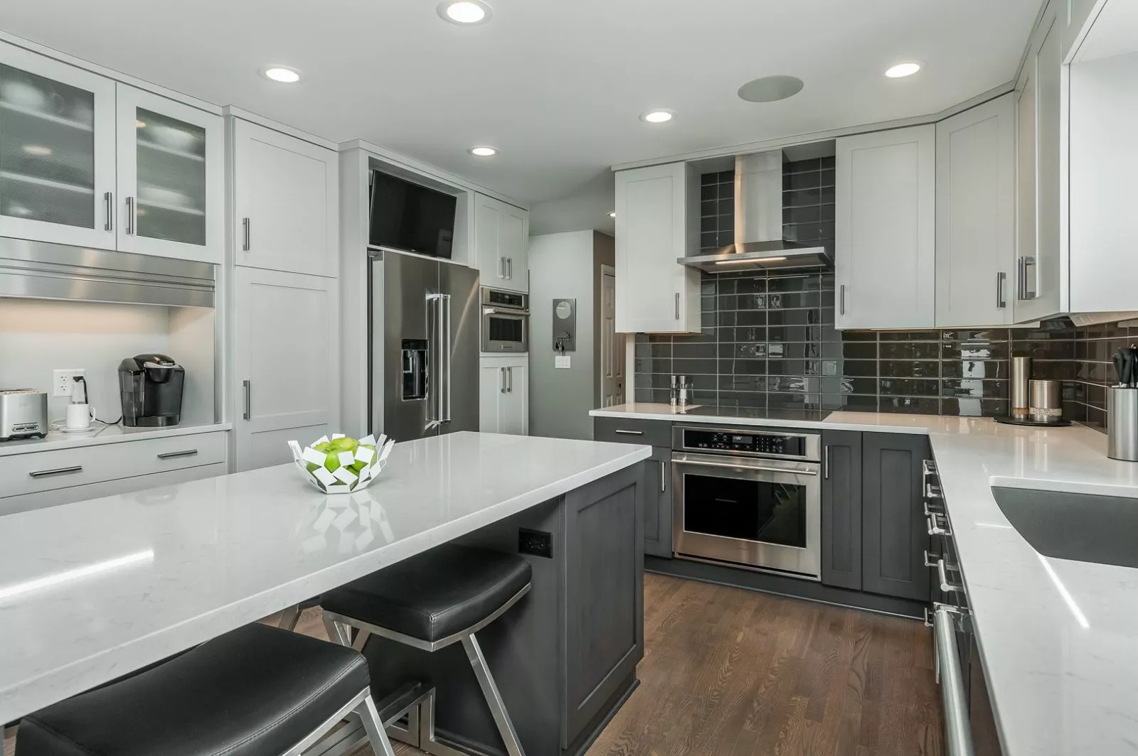 Modern kitchen with island, drawers, cabinets, silver appliances, and polished stone countertops