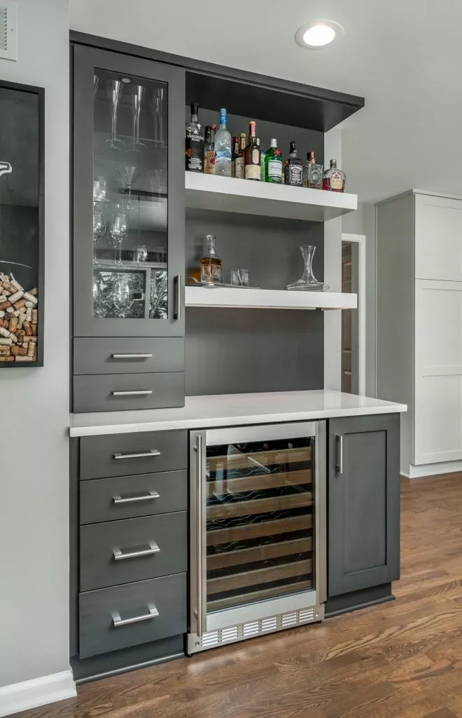 Grey cabinet installation including glass door wine cooler, wine glasses & alcohol on shelving
