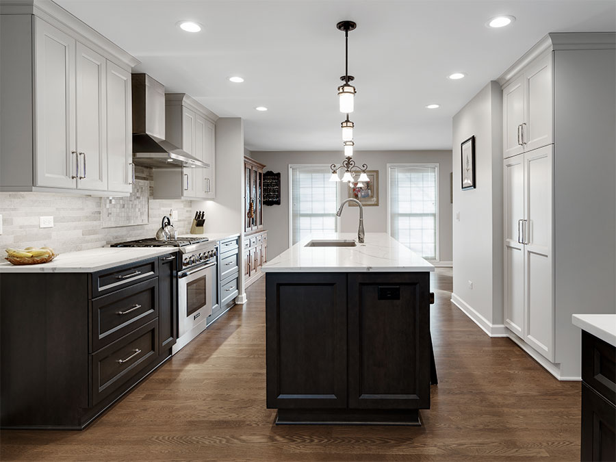 Modern kitchen with island, appliances, cabinets, drawers, and white polished stone countertops