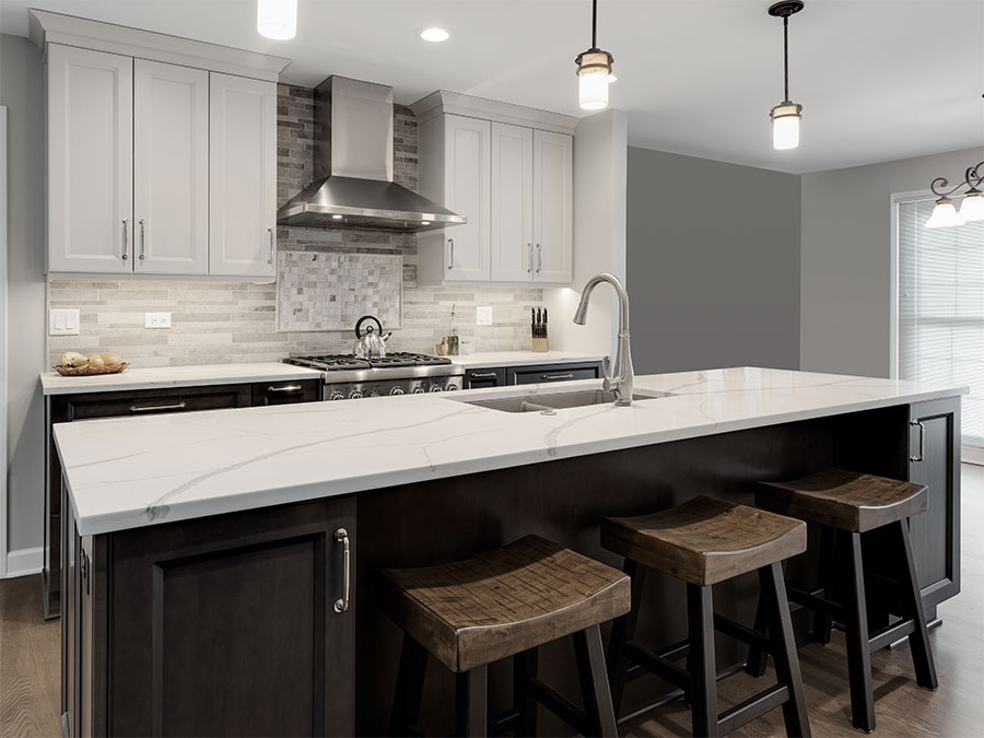 Modern kitchen with island, appliances, cabinets, drawers, and white polished stone countertops