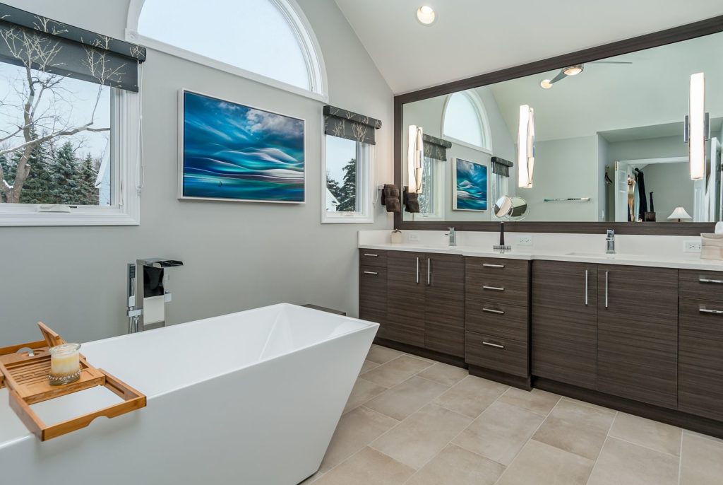 Bathroom with large vanity mirror charcoal cabinets chrome finishes white garden tub and tile floors