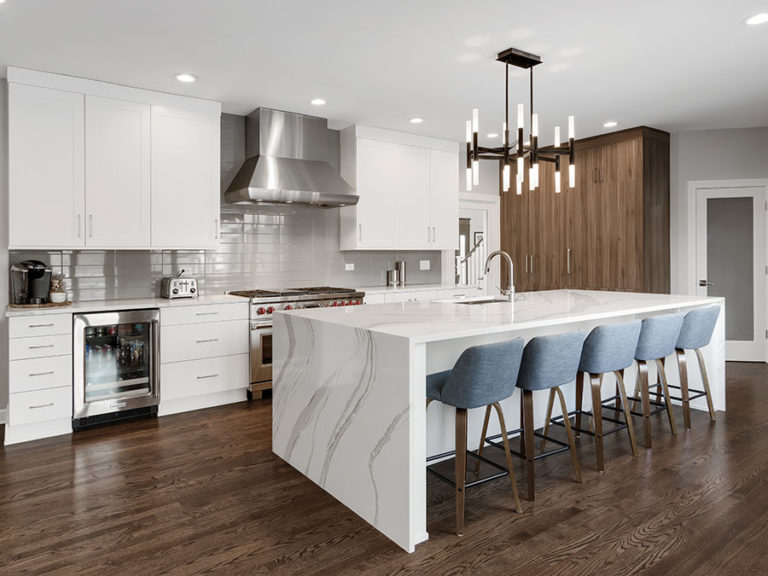 Kitchen white cabinets white marble waterfall island hardwood floors stainless steel hooded vent