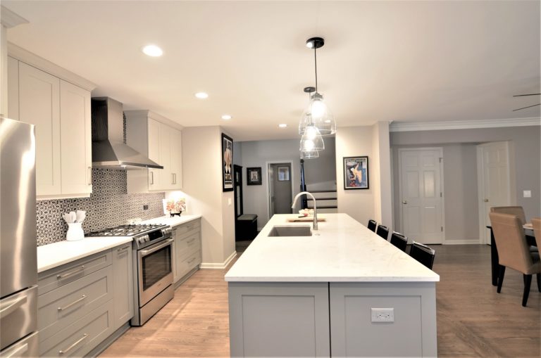 Open Kitchen white stone island grey cabinets glass pendant lighting with view of mudroom