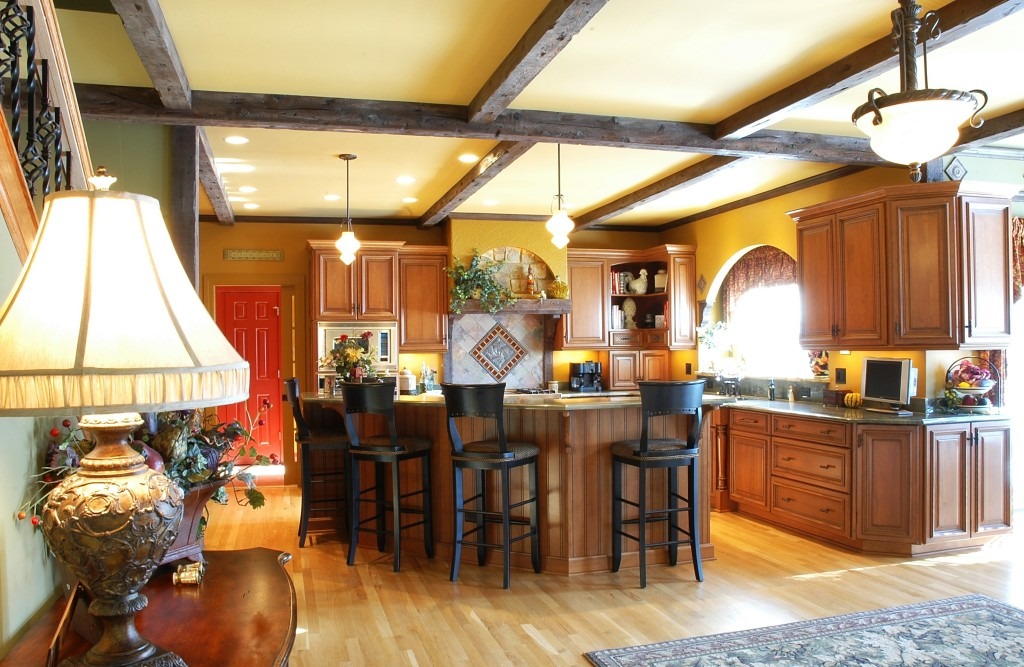 Kitchen with island and barstools oak cabinets hardwood floors ceiling beams and pendant lights