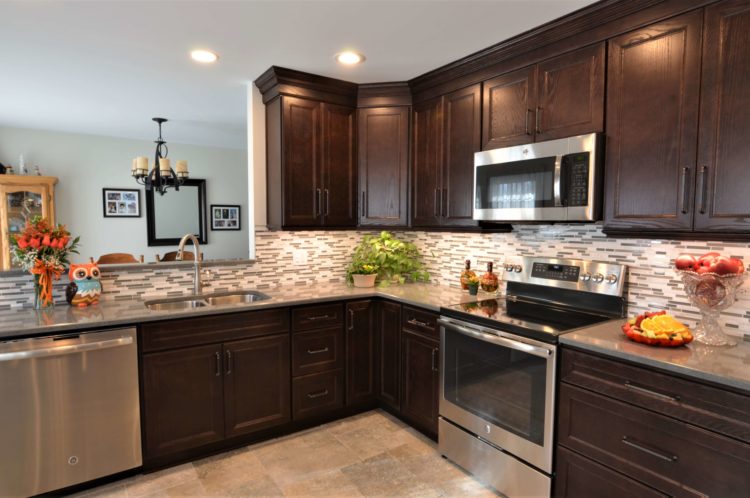 Kitchen with dark stained cabinets skinny neutral subway tile backsplash stainless steel appliances