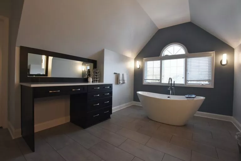 bathroom with white garden tub long vanity with dark cabinets chrome finishes blue painted walls