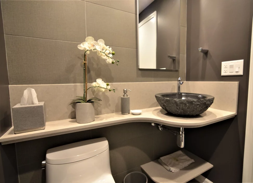 Hotel bathroom vanity with stone vessel sink grey accents and neutral countertop
