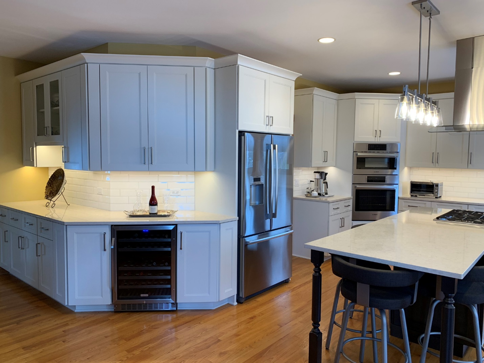 Kitchen with hardwood floor white cabinets stainless steel appliances island chrome pendant lights