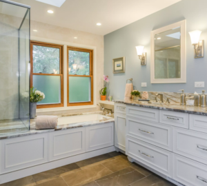 Remodeled bathroom with tile floors, white cabinets, granite countertops, and separate soaking tub and glass-enclosed shower.